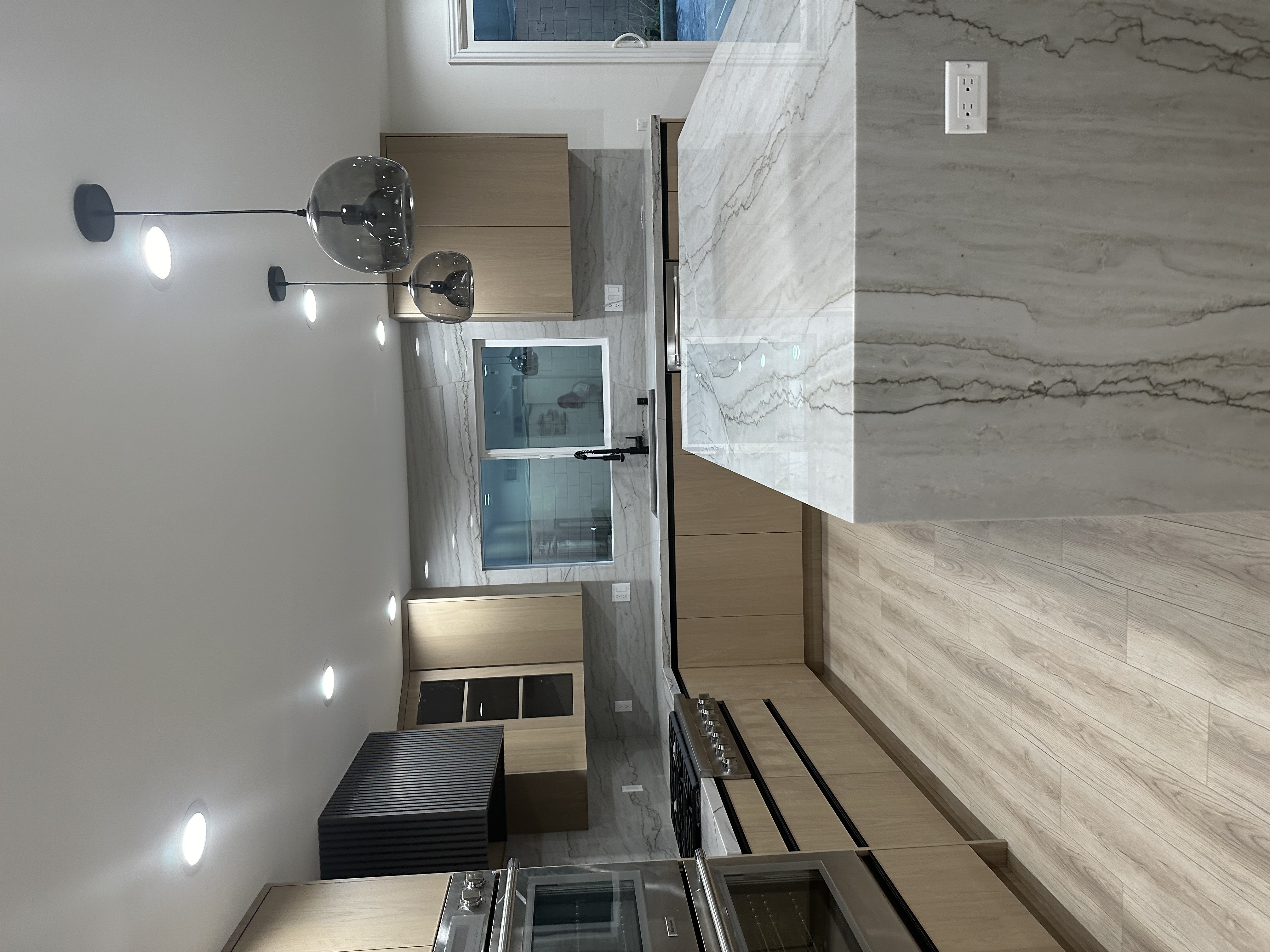 Calabasas kitchen remodel by Master Kitchen — light oak European frameless cabinets, quartzite waterfall island and fluted black range hood