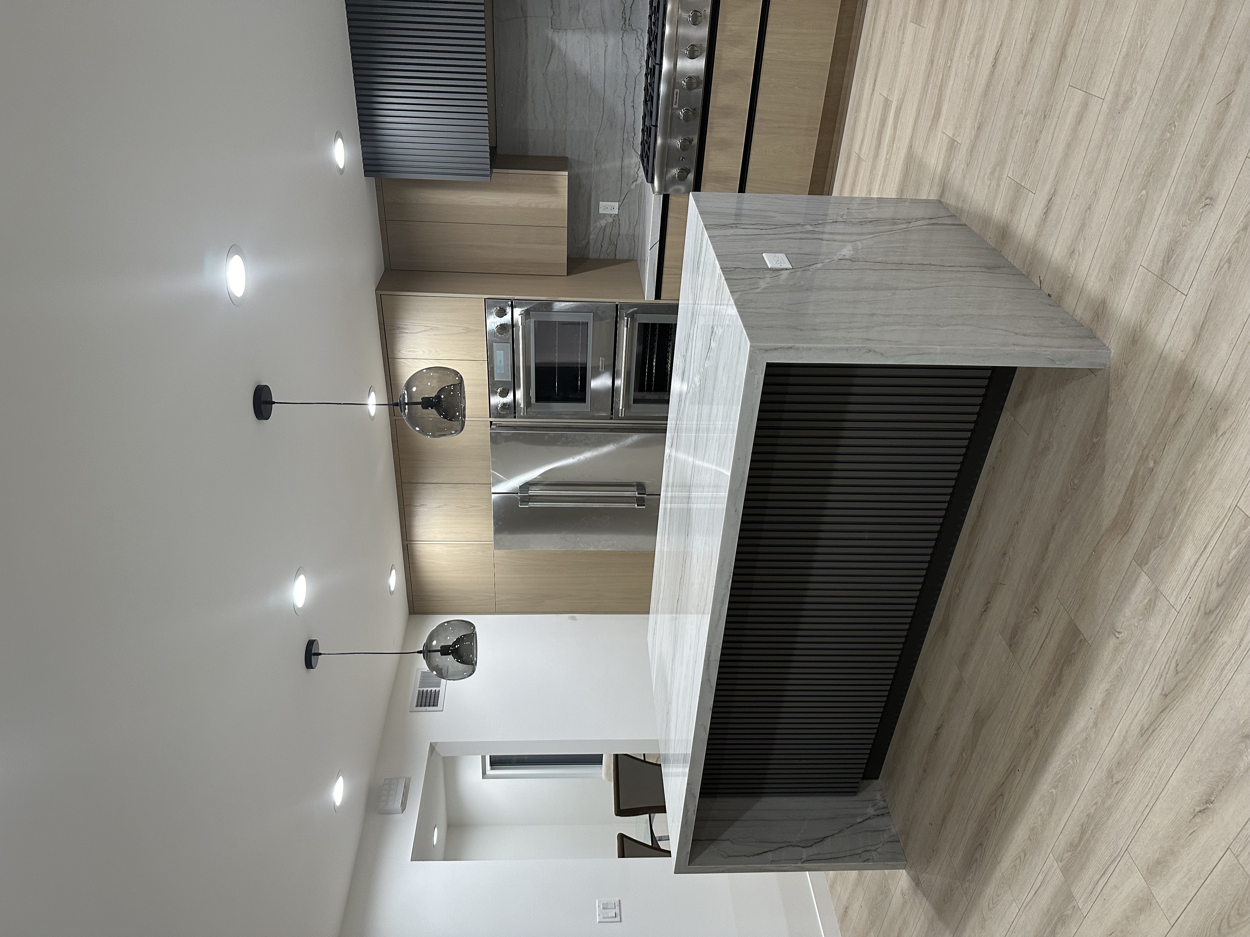 Calabasas kitchen wide view — integrated paneled refrigerator and fluted black island base