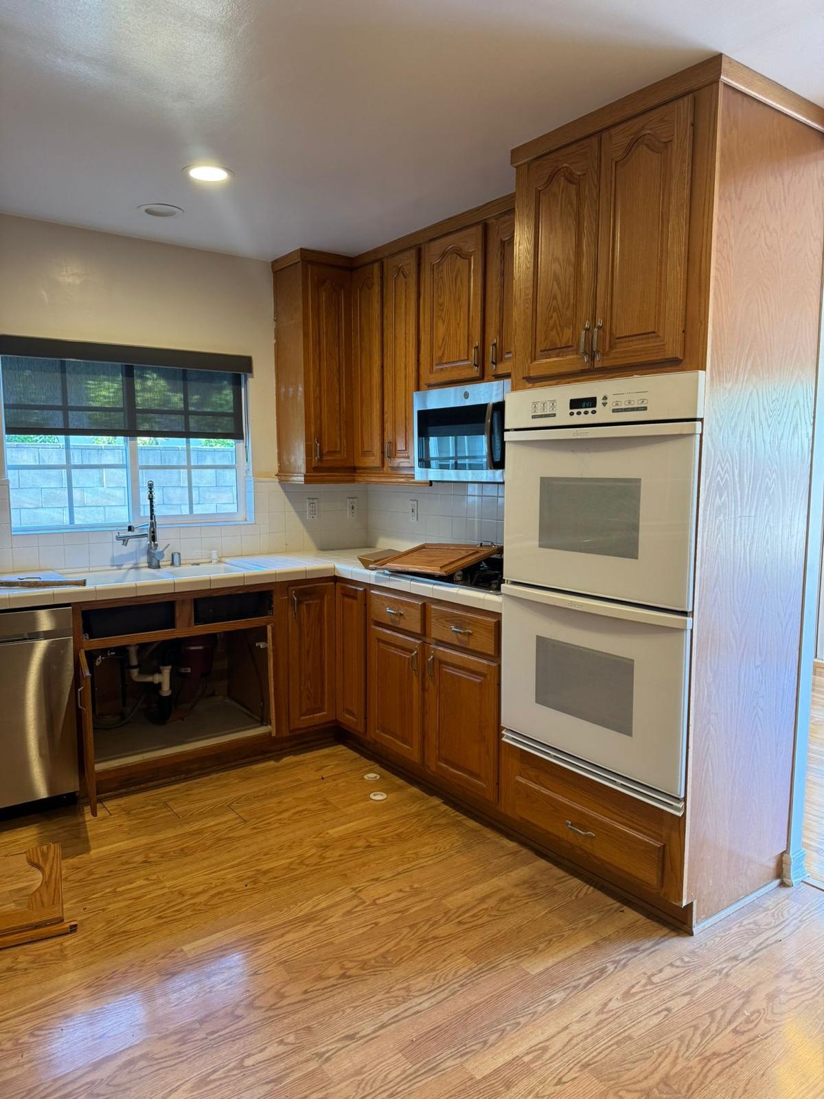 Woodland Hills kitchen before — oak raised-panel cabinets with white tile counters and double oven