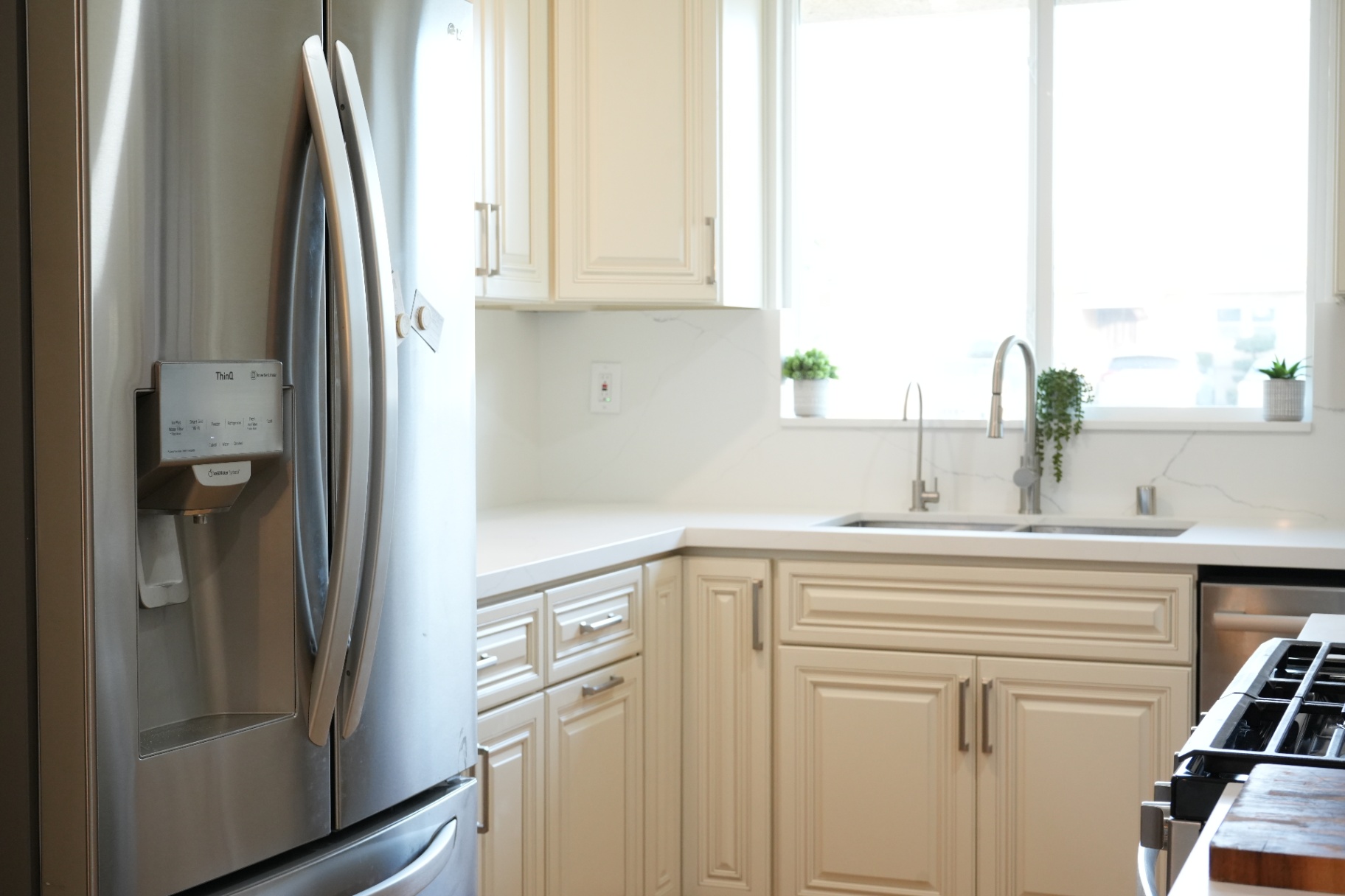 La Puente kitchen wide view — LG stainless refrigerator, quartz counters and bright window