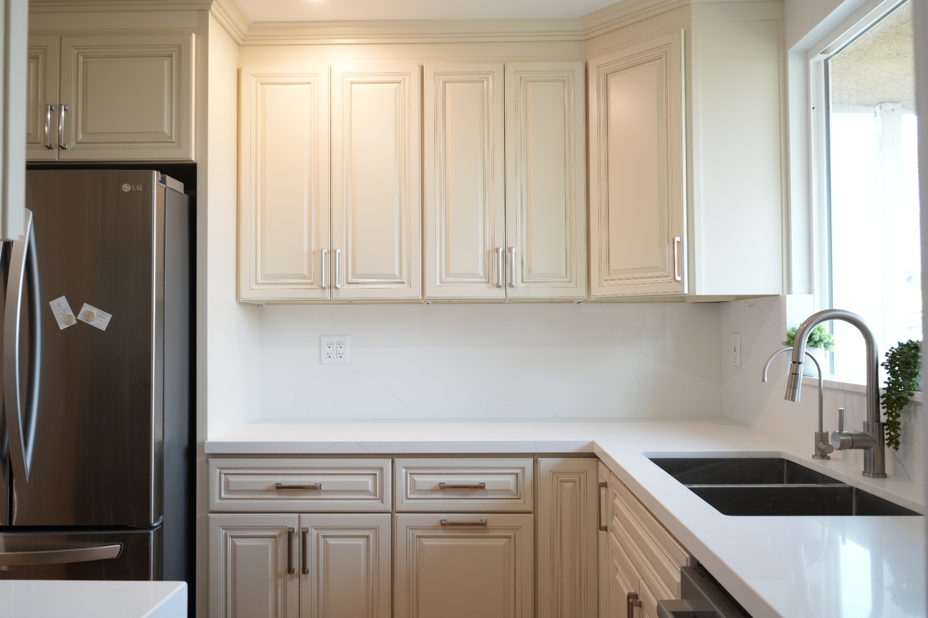 La Puente kitchen upper cabinetry — detailed cream raised-panel doors with brushed nickel pulls