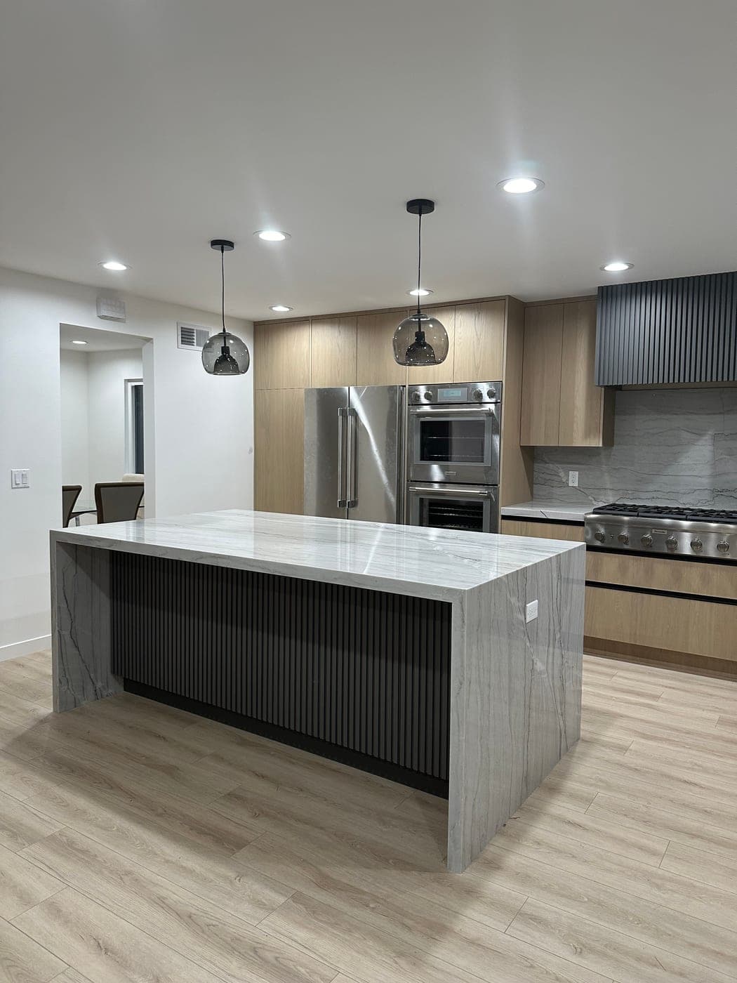 Calabasas kitchen with rift oak cabinetry, a fluted black island base and a quartzite waterfall island