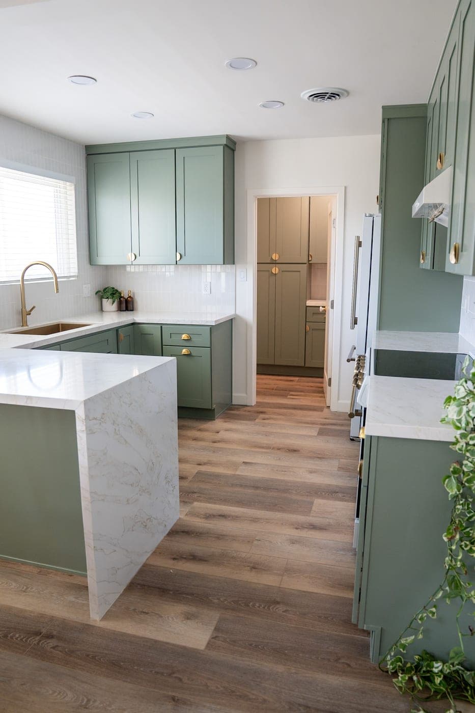Marble waterfall peninsula with the walk-in pantry beyond, in the same sage green