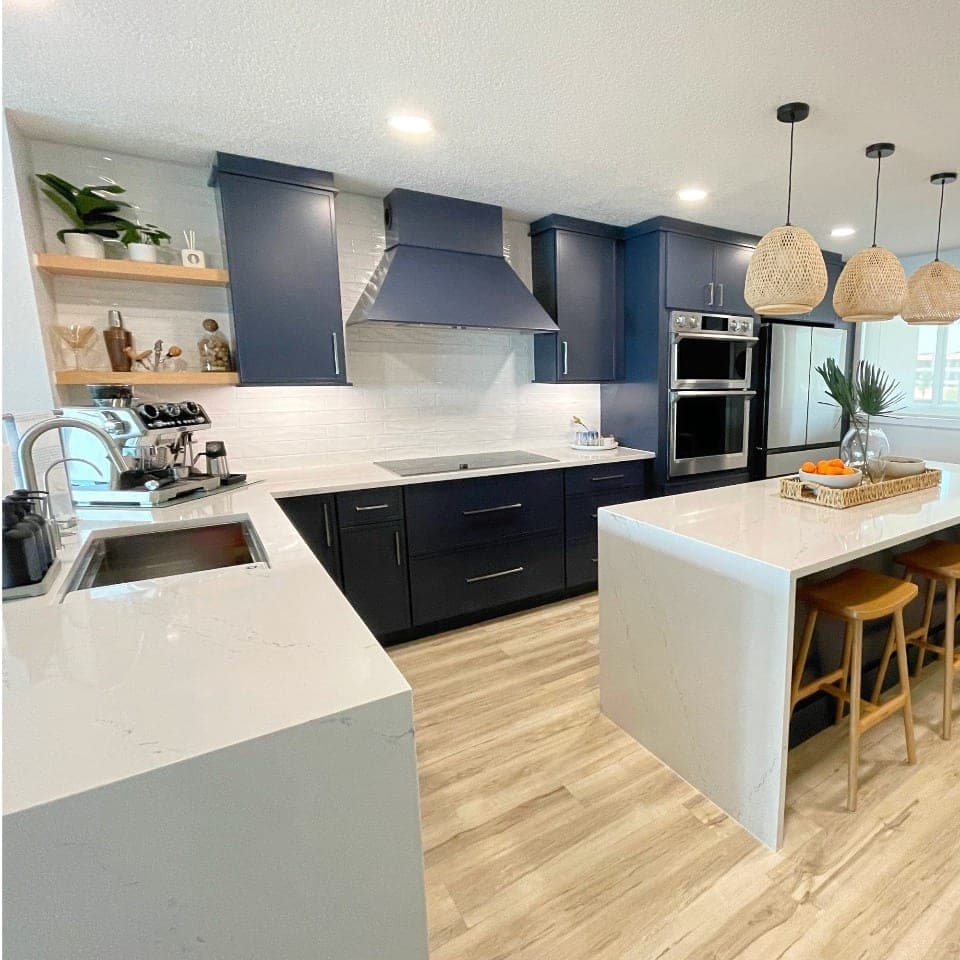 Santa Monica kitchen with navy cabinetry, a white quartz waterfall island and woven pendants