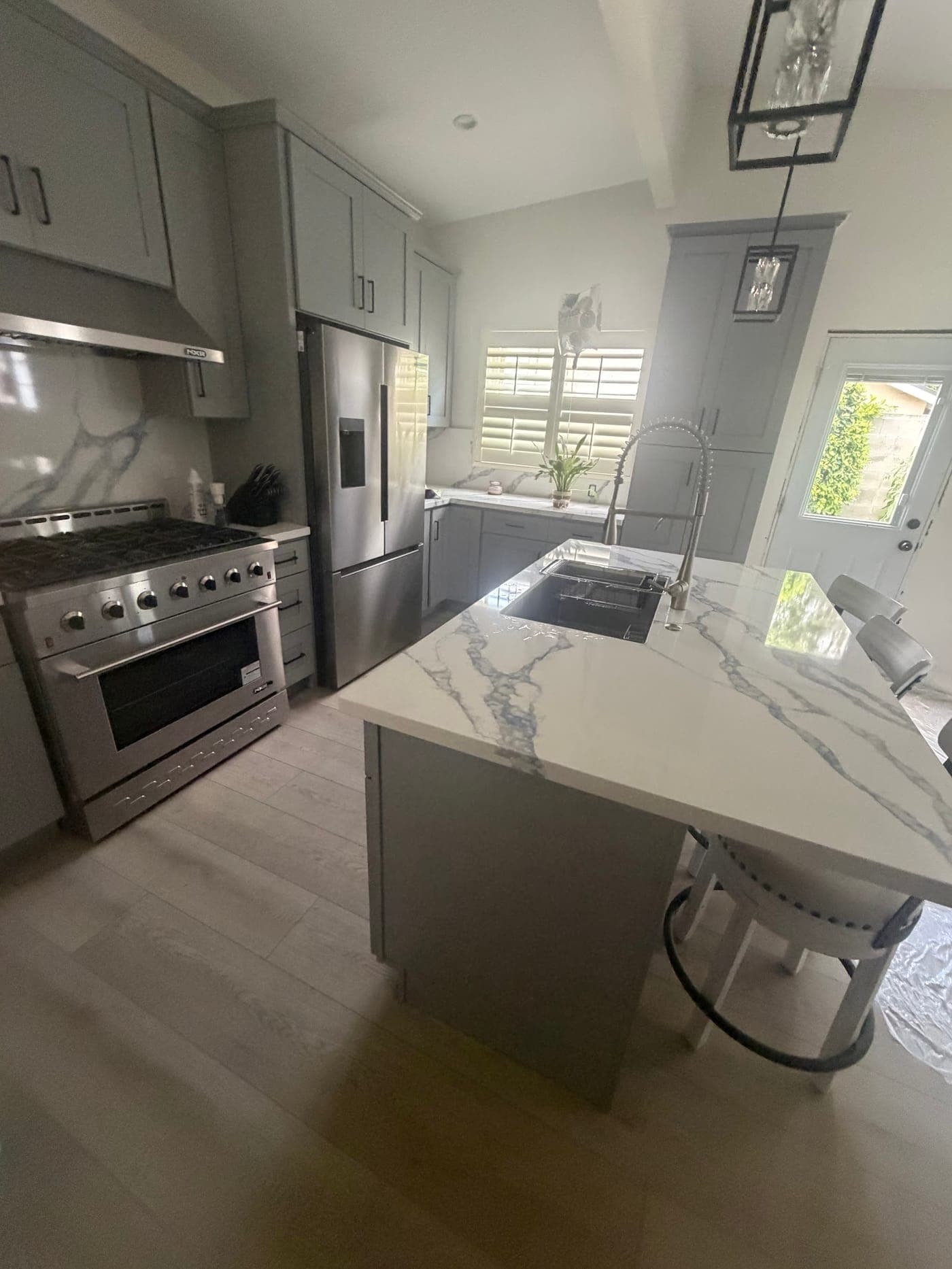 Gray Shaker cabinets, a stainless range and an island with a blue-veined white countertop