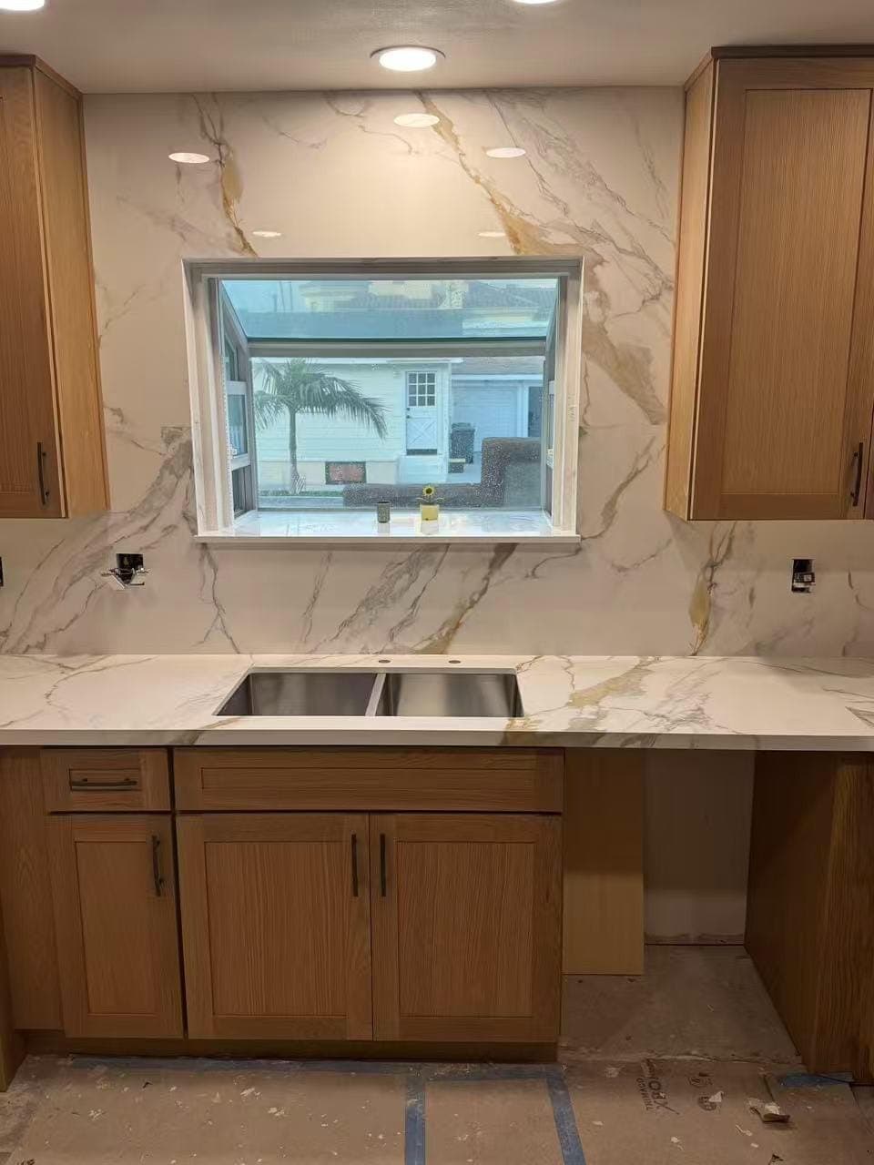 Oak Shaker cabinets and a gold-veined slab backsplash around the sink window