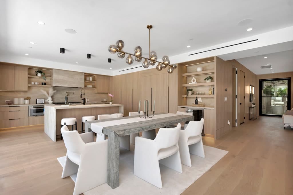 The finished West Hollywood kitchen seen from the dining area: oak cabinetry, a stone island and a professional range