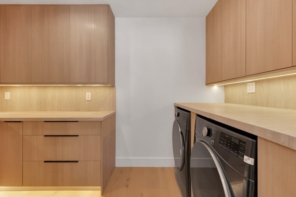 Laundry room in matching oak cabinetry with a stone counter