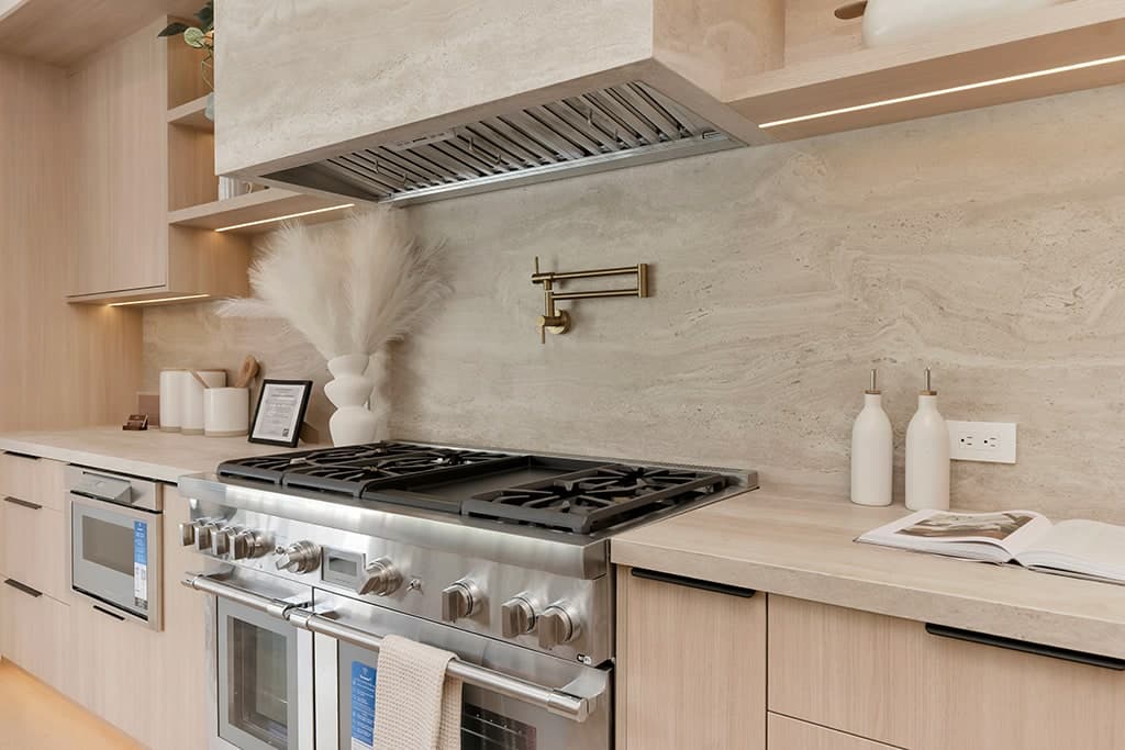 Close view of the range, the stone backsplash and the hood